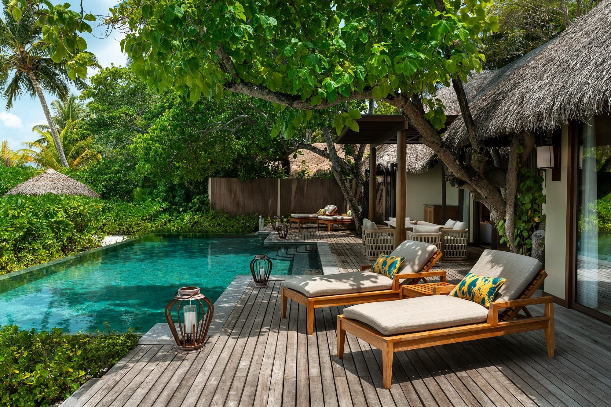 Private pool and sun loungers on a timber deck shaded by tropical trees